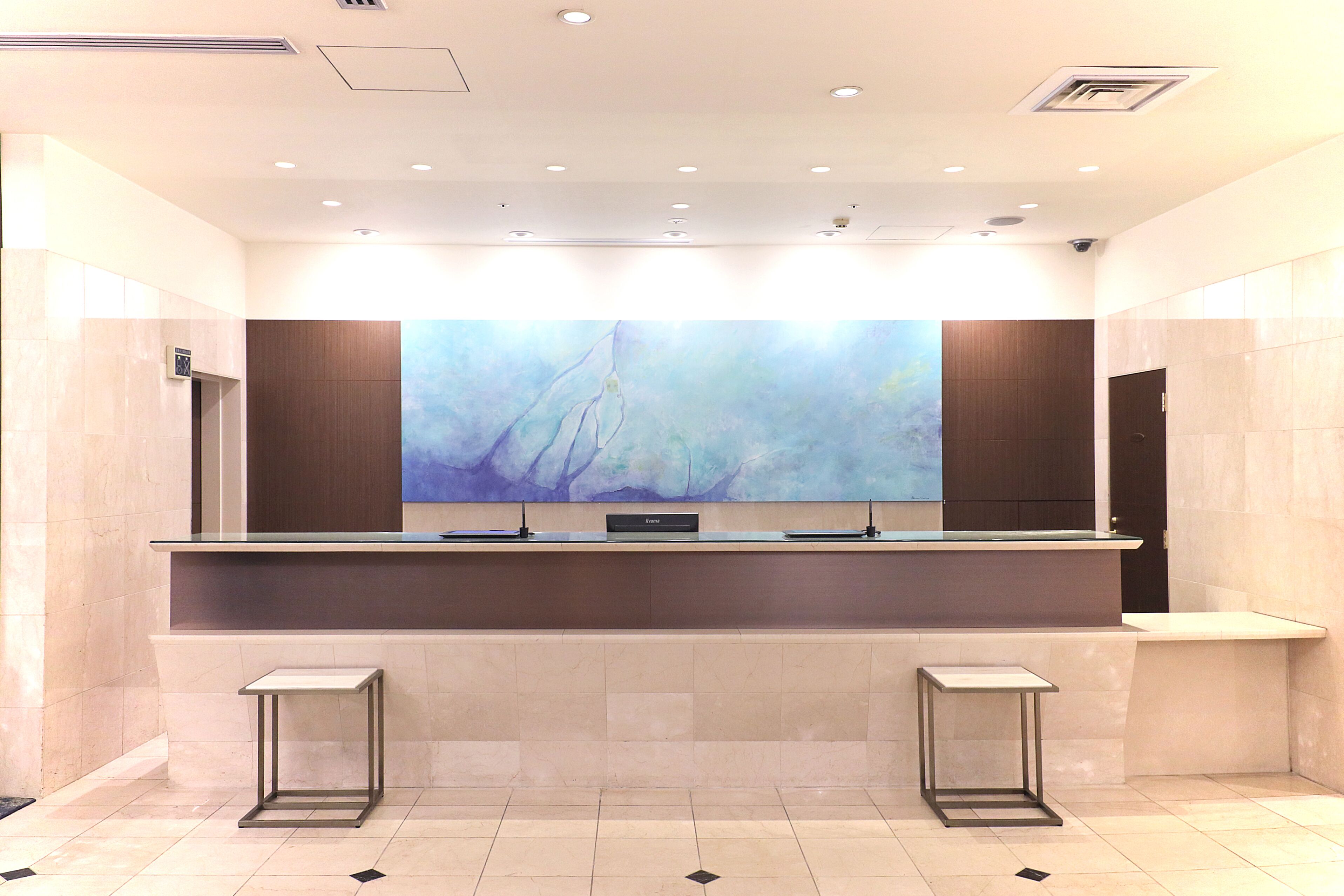 A modern reception area with a large abstract painting, a reception desk, and two small tables.