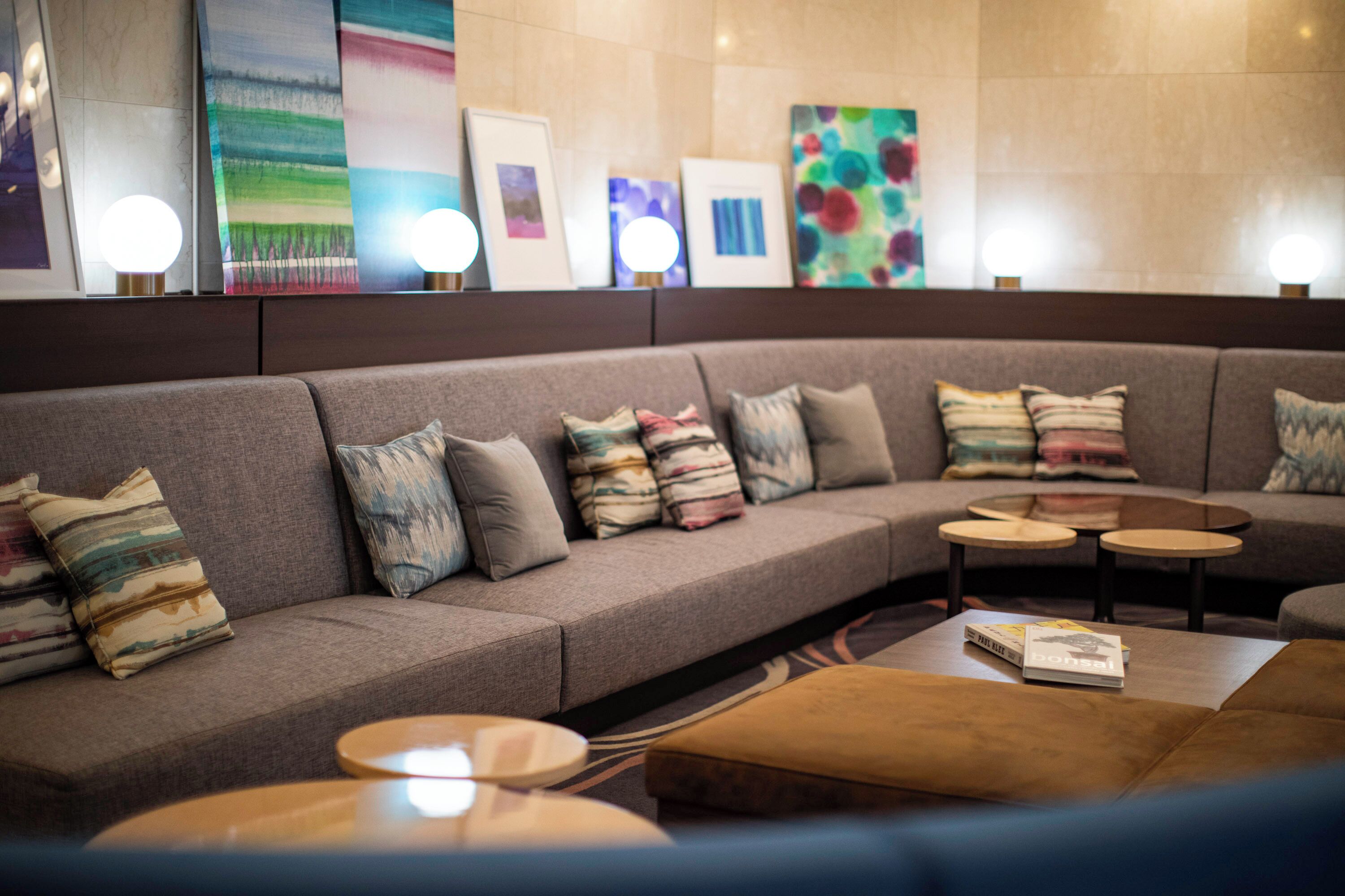 A modern lounge area with a sofa, round tables, and framed artwork on the wall.