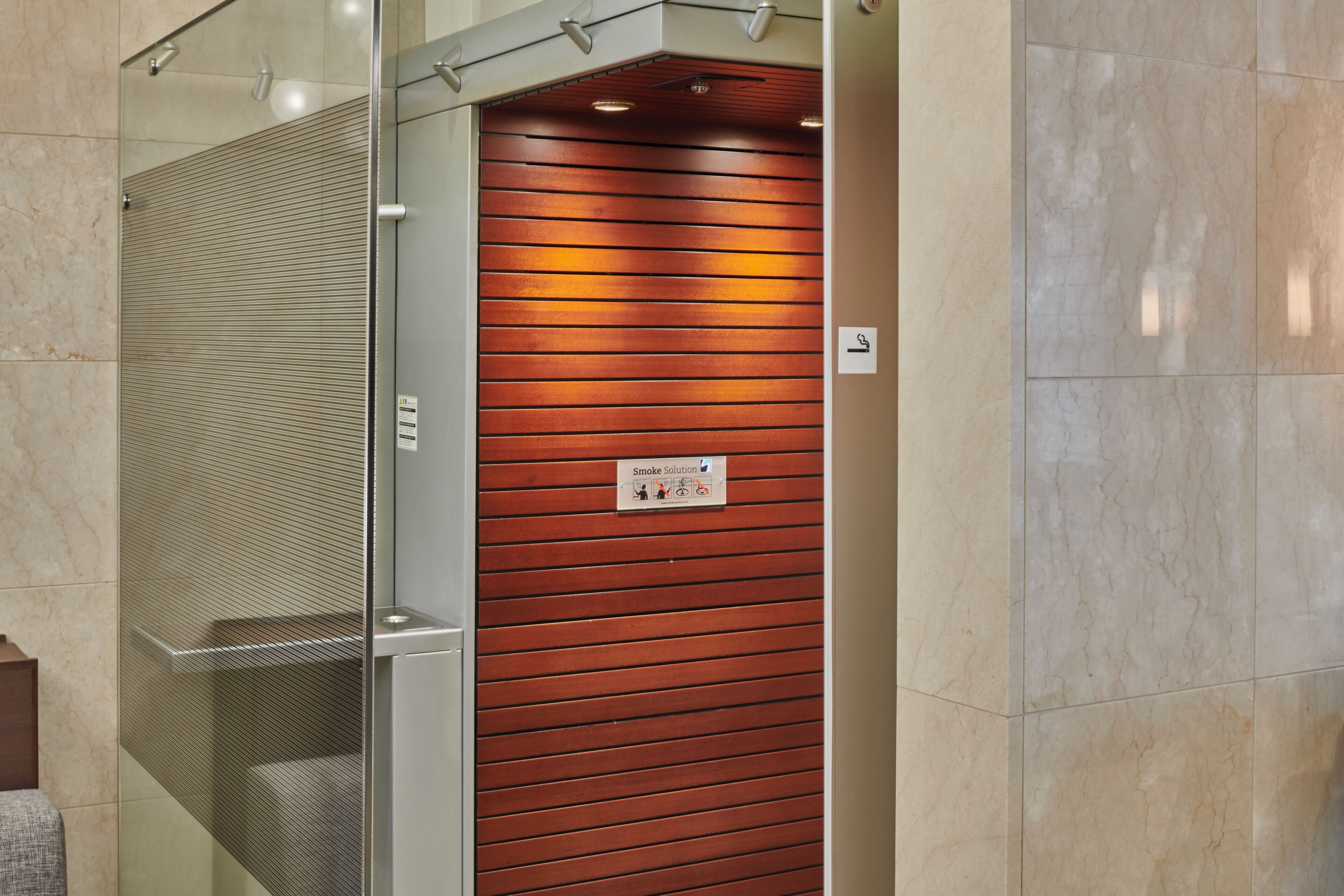 A modern elevator with a metallic interior and a wooden panel exterior.