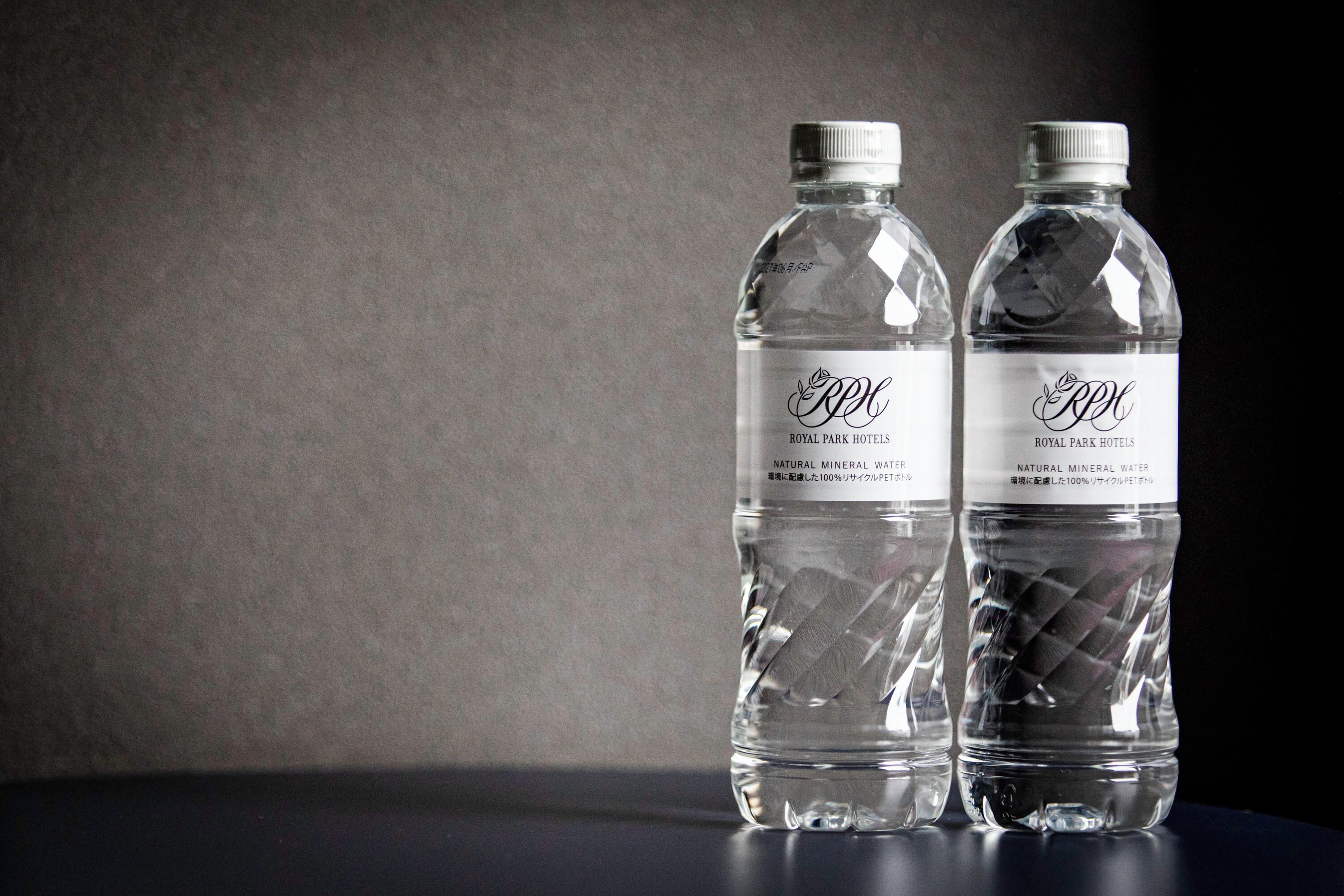 Two clear plastic bottles with labels, placed on a dark surface against a plain background.