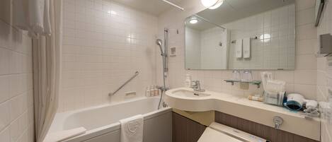 A modern bathroom with a bathtub, a sink, a toilet, and a mirror.