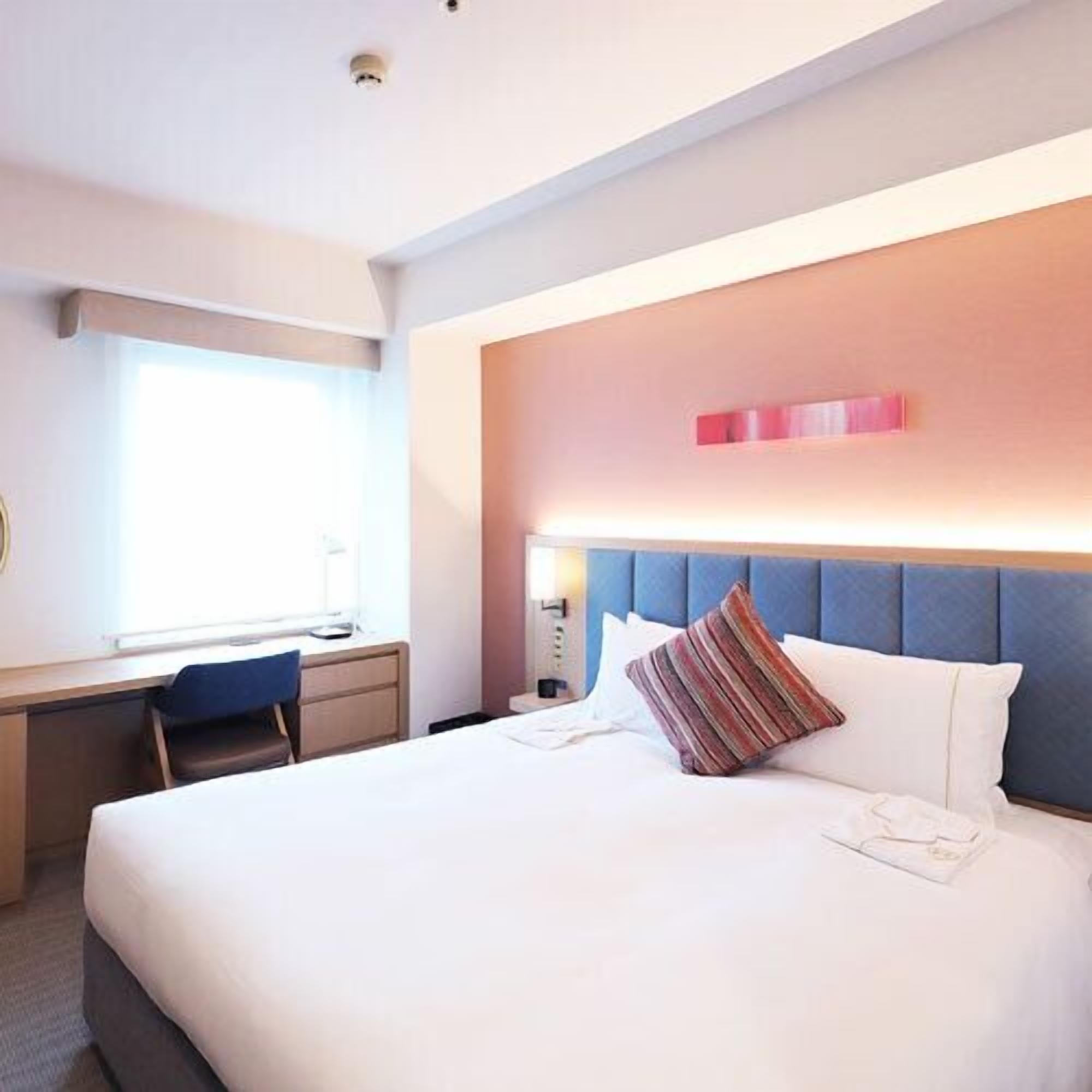 A hotel room with a bed, a desk, and a chair.