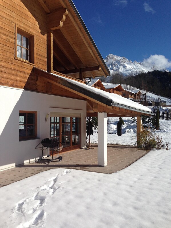 A wooden chalet with a covered patio, large windows, and a view of snow-covered mountains. - Modern living in the middle of the nature mountains (Novale)