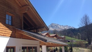 A wooden chalet with a sloped roof, large windows, and a view of snow-capped mountains in the background. - Modern living in the middle of the nature mountains  (Novale)