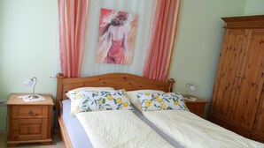 Une chambre à coucher avec un lit en bois, deux tables de chevet, une armoire et un tableau accroché au mur.