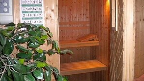 Un sauna en bois avec une affiche accrochée au mur, un banc et une plante.
