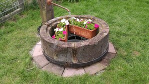 Una jardinera de piedra circular con flores y un caño.