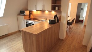 Una cocina moderna con armarios de madera, horno empotrado, microondas y cafetera.