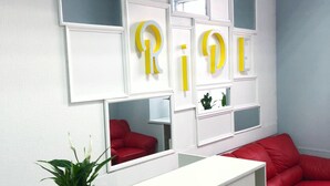Un espace de bureau moderne avec un bureau de couleur blanche, un canapé en cuir rouge et des miroirs décoratifs ornés de lettres jaunes.