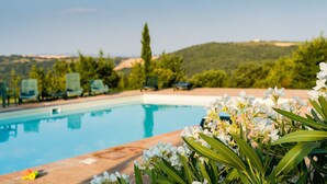 A swimming pool with lounge chairs and a view of hills. - Agriturismo Santa Maria (San Venanzo)