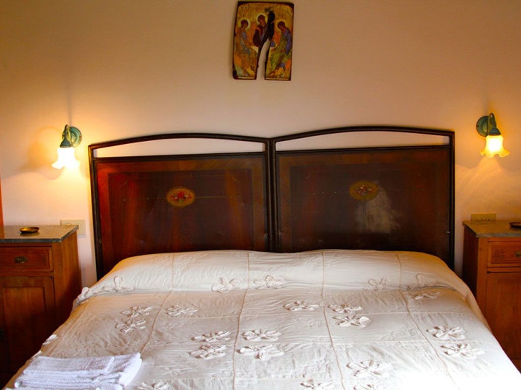 A bed with a wooden headboard, two bedside tables, and wall-mounted lamps.