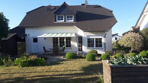 A two-story house with a tiled roof, a covered patio with chairs, and a well-maintained garden. - Cottage on the mountain (Strohn)
