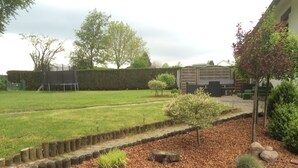 A well-maintained garden with a lawn, a wooden fence, and a variety of shrubs.