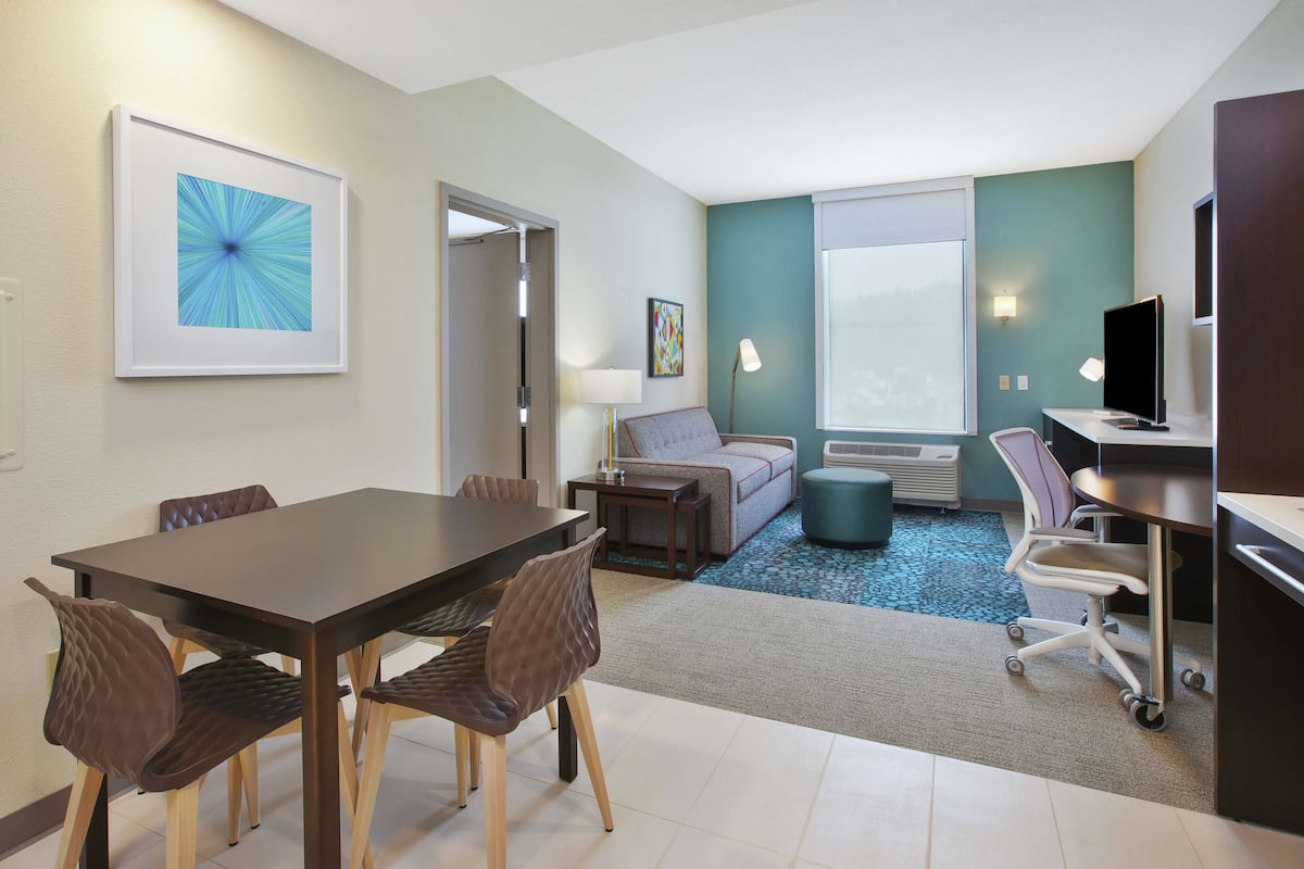 Een moderne hotelkamer met een zithoek, een bank, een televisie en een groot raam.