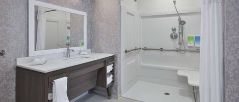 A modern bathroom with a large mirror, two sinks, a shower with a glass door, and a towel rack.