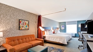 Habitación de hotel con sofá, dos camas, escritorio y televisión.