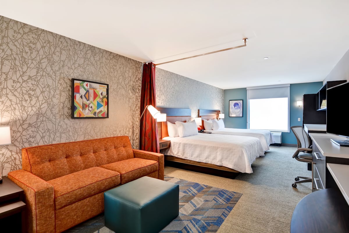Een hotelkamer met een bank, twee bedden, een bureau en een televisie.