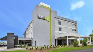 A modern hotel building with a sign reading "HOME 2 SUITES BY HILTON".