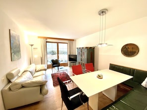 A modern living room with a sofa, a dining table, and a TV.