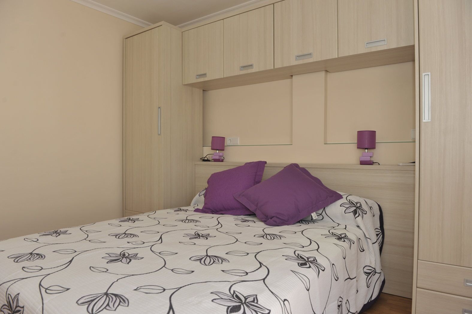 Un dormitorio con una cama, dos lámparas de noche y un armario.