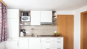 A compact kitchenette with a microwave, coffee maker, and sink.