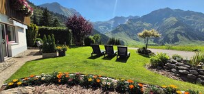 A hotel with a grassy lawn, outdoor seating, and a mountain view. - Comfortable apartment with terrace, sunbathing area, playground, free Wi-Fi, pets (Schröcken)