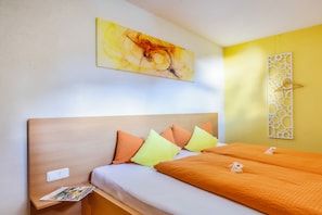 A hotel room with a bed, pillows, a wall art piece, a decorative panel, and a magazine on the nightstand. - Comfortable apartment with terrace, sunbathing area, playground, free Wi-Fi, pets (Schröcken)