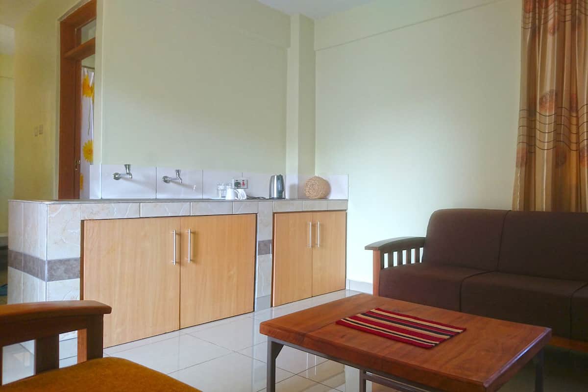 A compact living space with a kitchenette, a sofa, and a small table.
