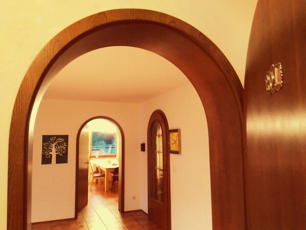 A hallway with wooden arches, a dining area in the background, and a door with a handle. - Holiday in the health resort Egloffstein near Nuremberg, ideal for group (Egloffstein)