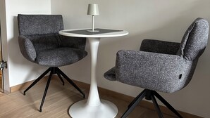 A room with a round white table, two grey upholstered chairs, a white floor lamp, and a painting of a landscape on the wall. - Tegernsee - Great, central apartment (Tegernsee)
