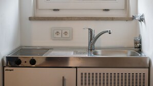 A kitchen with a stainless steel sink, a stove, and a window above the sink. - Tegernsee - Great, central apartment (Tegernsee)