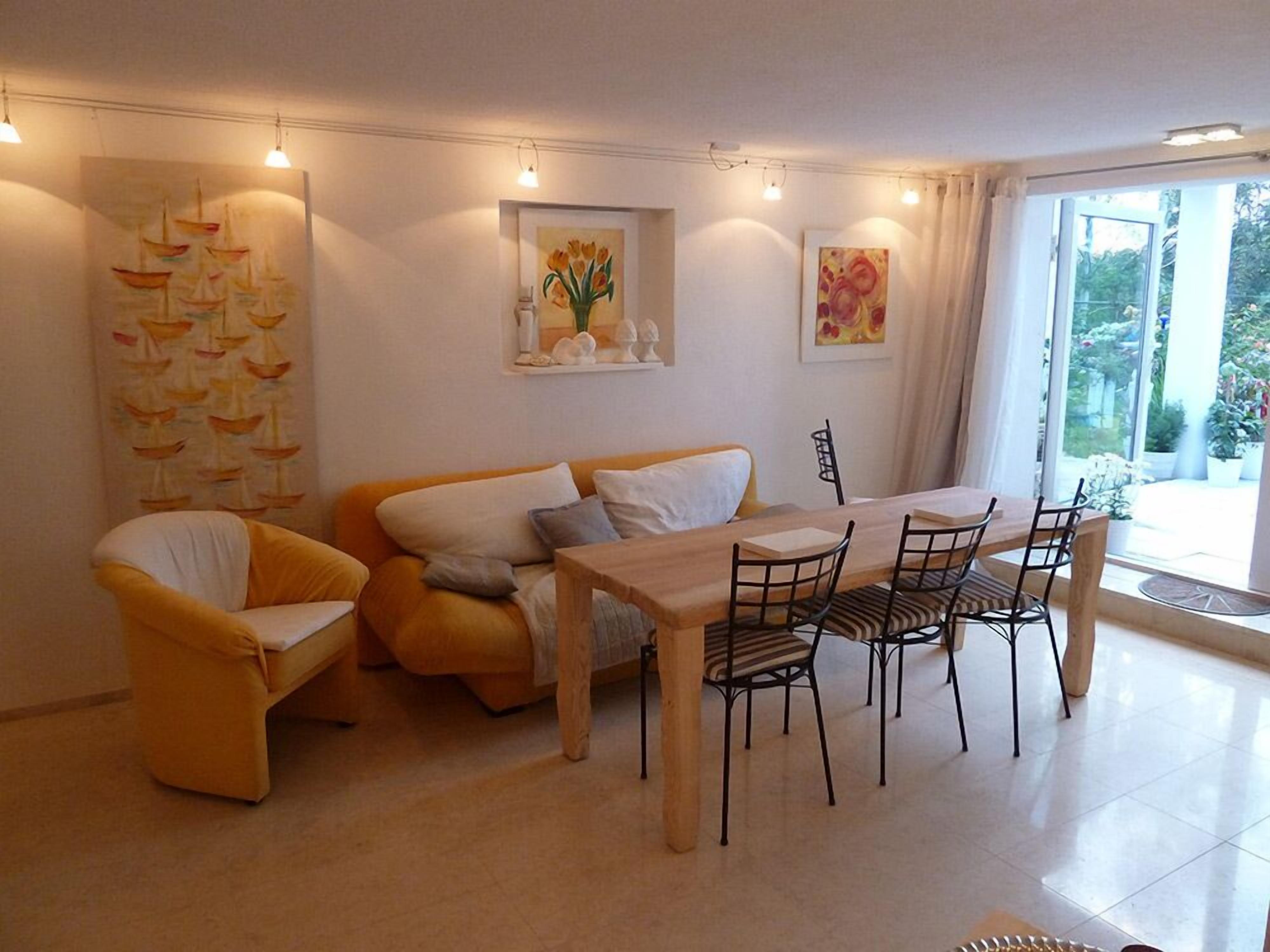 Un salon moderne avec un canapé, une table à manger et des chaises, ainsi que des œuvres d’art accrochées aux murs.