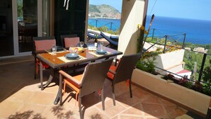 An outdoor dining area with a table set for four, overlooking a scenic view of the sea and hills. - Dream location in Costa Canyamel (Canyamel)