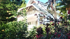 A two-story building with a balcony, surrounded by lush greenery and flowering plants. - Apartment La Batie self catering for 2 on Beau Vallon (Mahe)