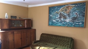 A living room with a green sofa, wooden cabinet, and a painting of a horse.