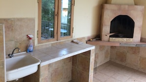 A kitchen with a sink, a window, and a wood-fired oven.
