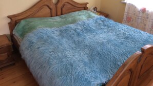 A bed with a wooden headboard and a fluffy blue blanket.
