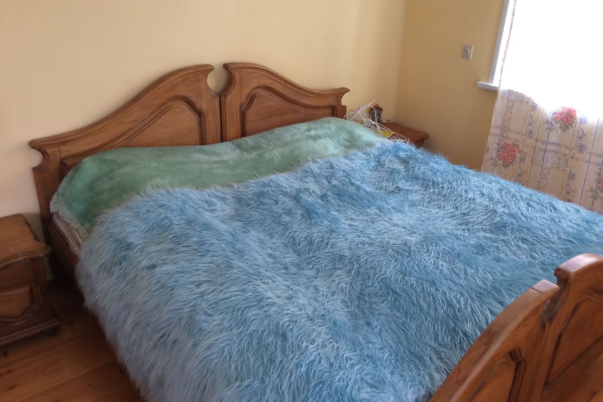 A bed with a wooden headboard and a fluffy blue blanket.