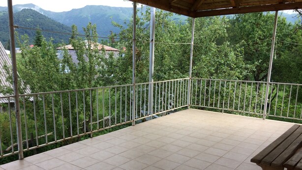 A balcony with tiled flooring, a metal railing, and a wooden bench.