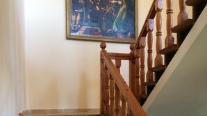 A wooden staircase with a handrail, leading to a landing where a framed painting is displayed on the wall.