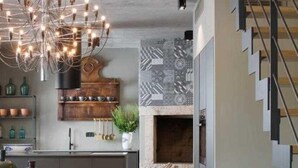 A modern kitchen with a wooden island, a chandelier, and a staircase.