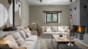 A modern living room with a fireplace, a sofa set, a coffee table, and abstract wall art.