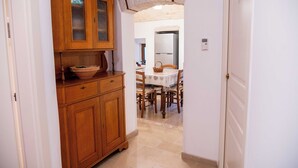 Una cocina con armarios de madera, una mesa de comedor con sillas y un refrigerador.