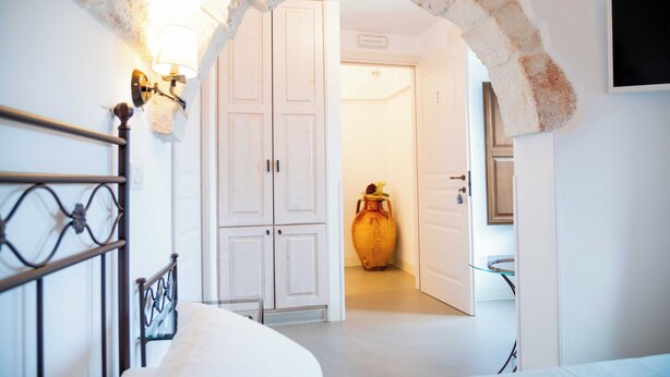 Un dormitorio con cama, armario y un arco de piedra.