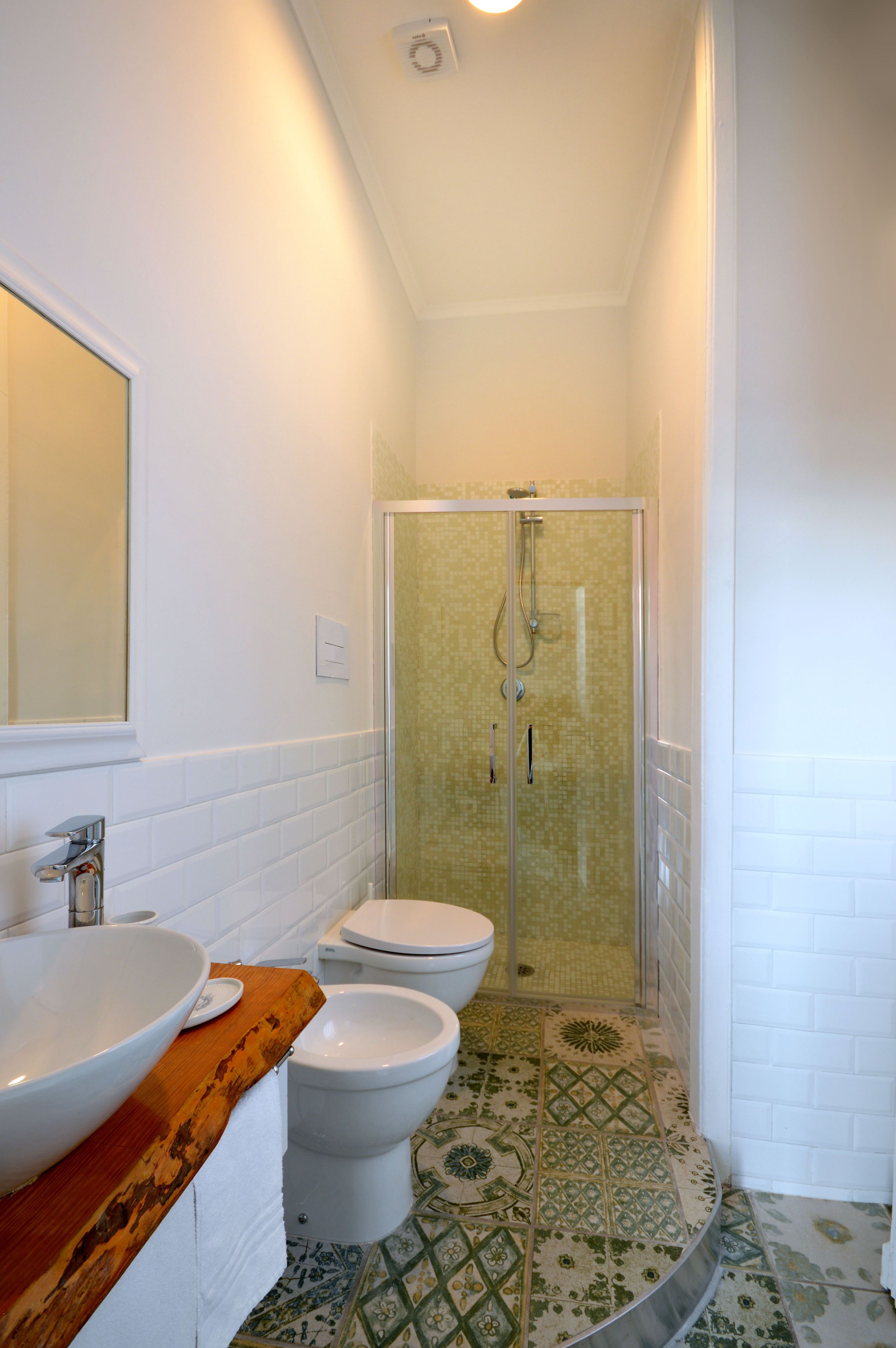 Un bany amb un lavabo blanc, un vàter i una dutxa amb envàs de vidre.