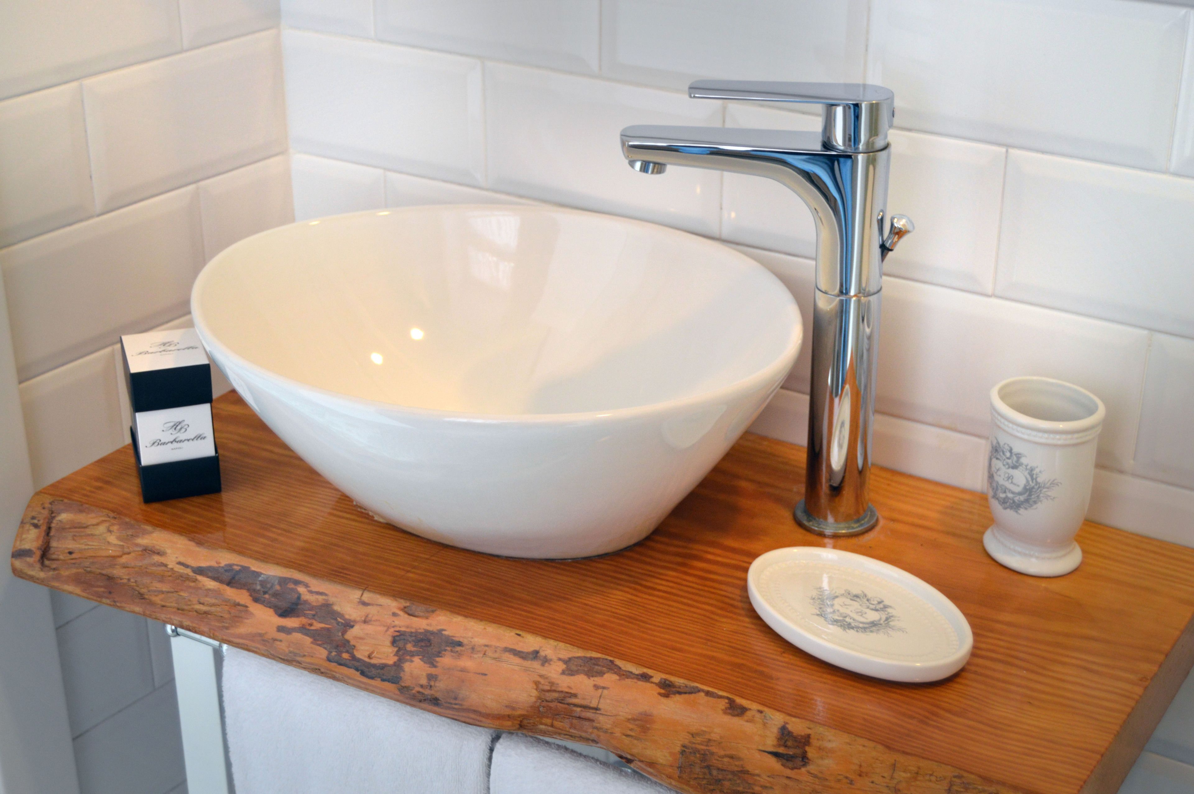 A white ceramic sink with a modern faucet, a small dish on the counter, and a decorative cup.