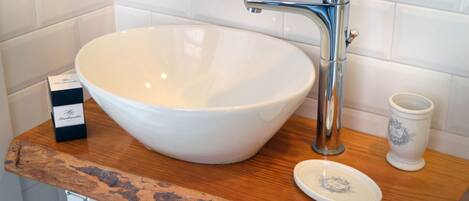 A white ceramic sink with a modern faucet, a small dish on the counter, and a decorative cup.