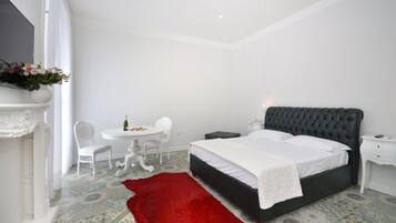A bedroom with a bed, a nightstand, a chair, a small table with a bottle, and a red rug.