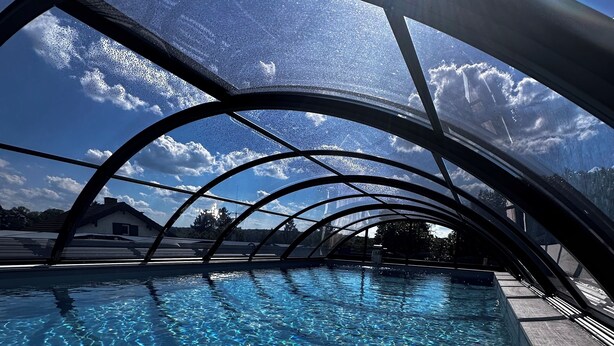 Una piscina d'aigua cristal·lina, envoltada per una estructura d'arc metàl·lic.