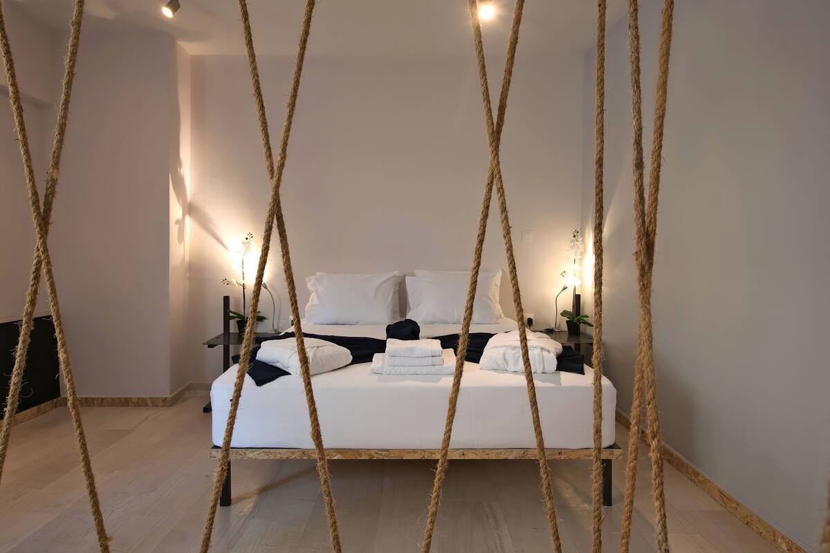 A bedroom with a bed, bedside tables, and wall-mounted lights.